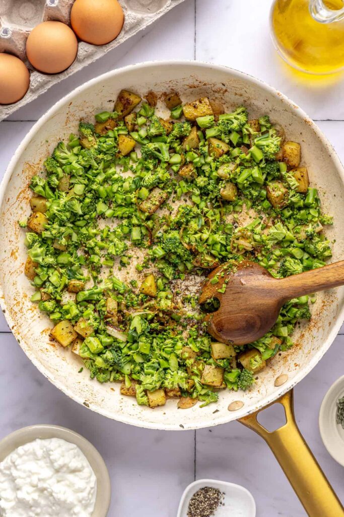 Potatoes, shallots, and broccolini cooking in skillet for Chicken & Veggie Egg Bake