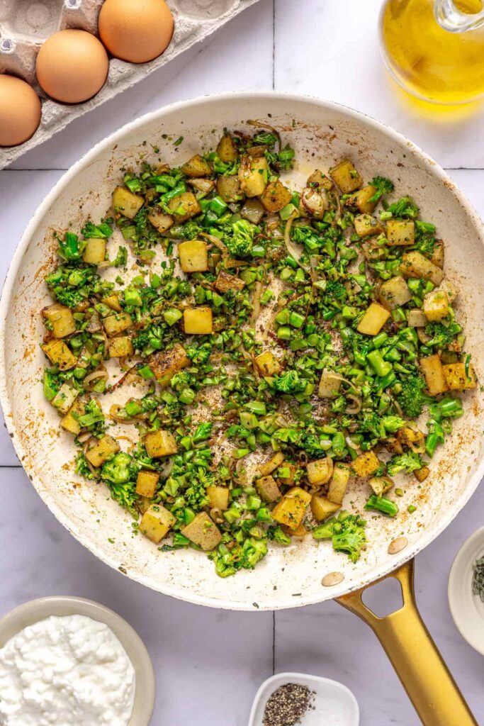 Potatoes, shallots, and broccolini cooking in skillet for Chicken & Veggie Egg Bake