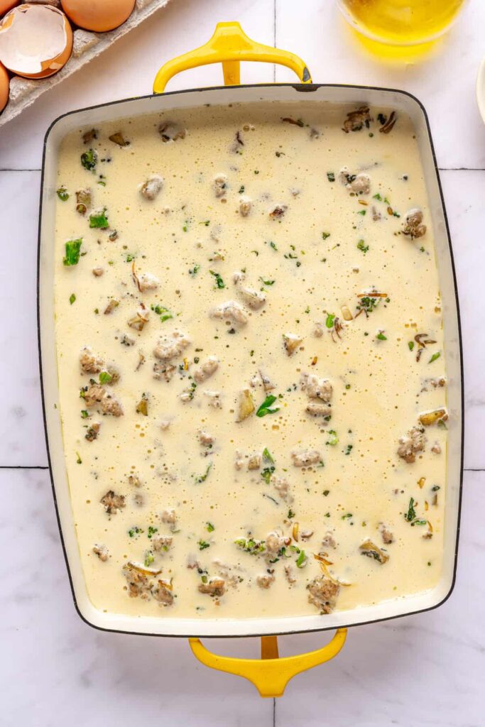 Unbaked Chicken & Veggie Egg Bake before topping with goat cheddar and sage in a 9x13 pan before baking