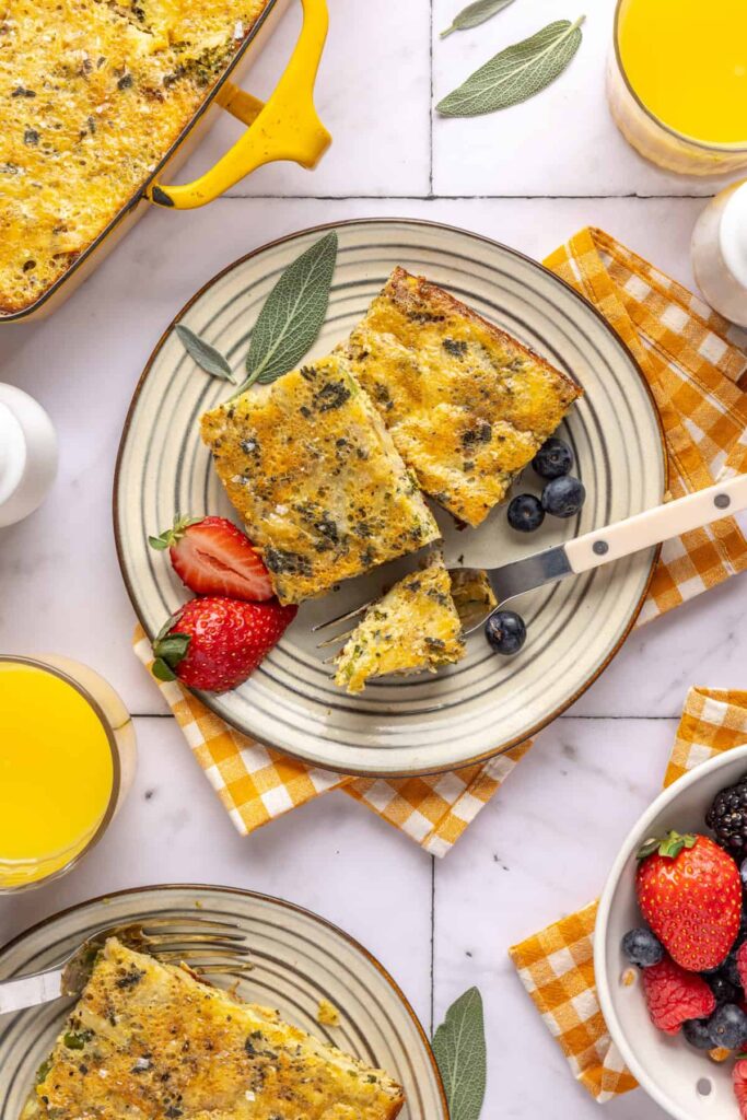 Plated slices of Chicken & Veggie Egg Bake with fresh berries and silverware