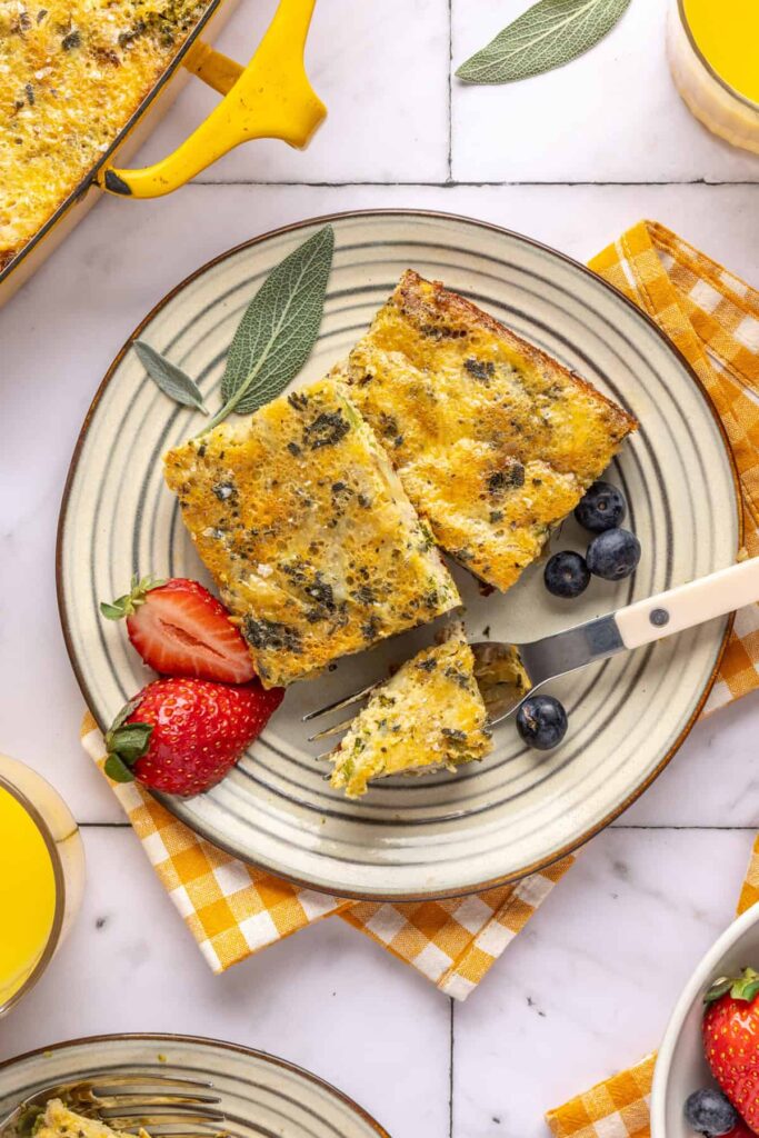 Plated slices of Chicken & Veggie Egg Bake with fresh berries and silverware