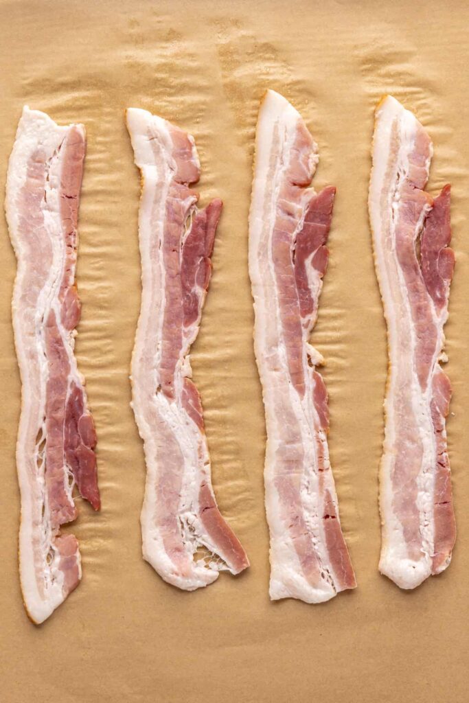 Applewood smoked bacon on parchment-lined baking sheet before baking