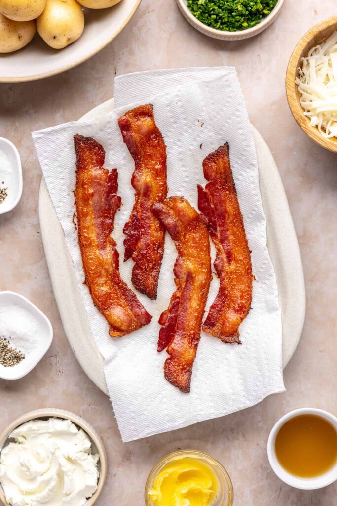 Crispy baked bacon pieces on a paper towel-lined plate