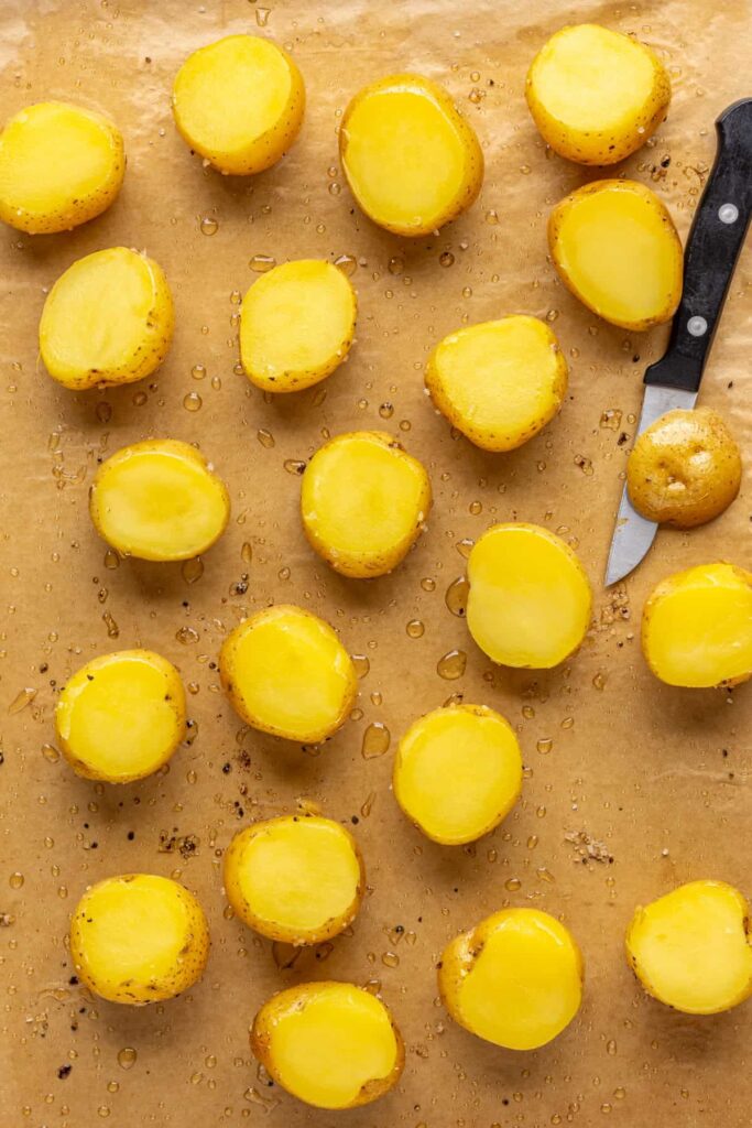 using a paring knife to slice off the top third of the baked mini Dutch potatoes for easy twice baked potatoes