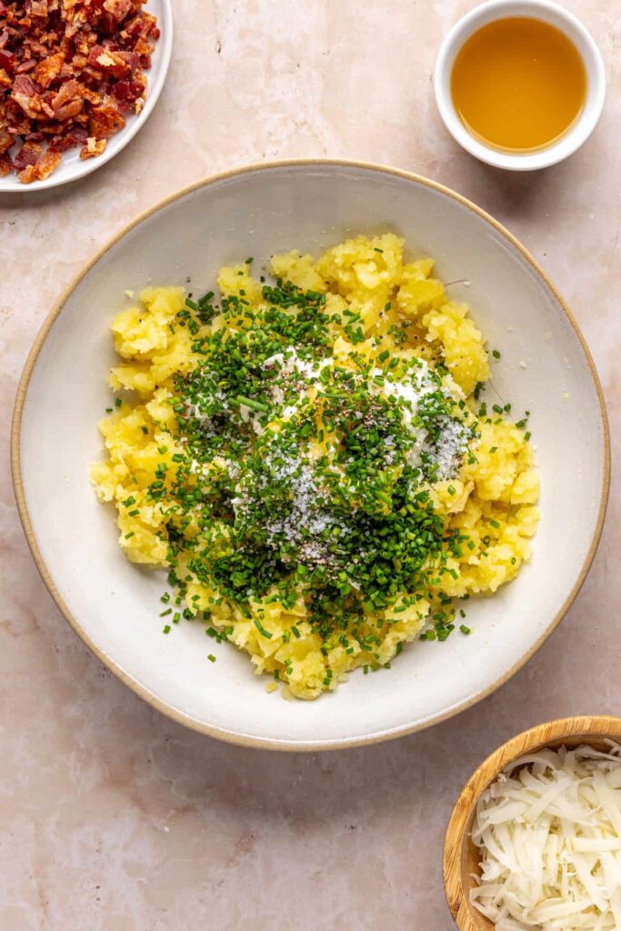 Mashed potato flesh in a bowl with goat cheese, ghee, and chives