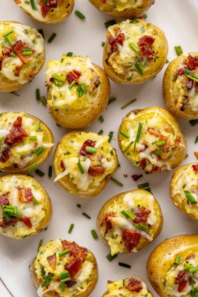 Close-up overhead of golden brown twice baked potatoes with cheesy filling, chives, and crispy bacon