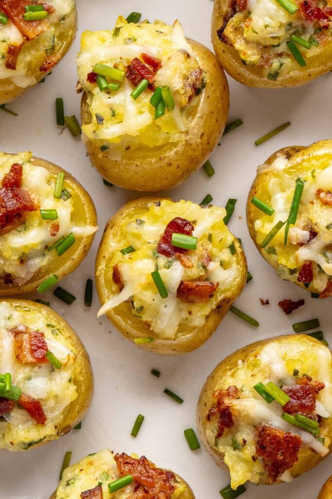 Close-up overhead of golden brown twice baked potatoes with cheesy filling, chives, and crispy bacon