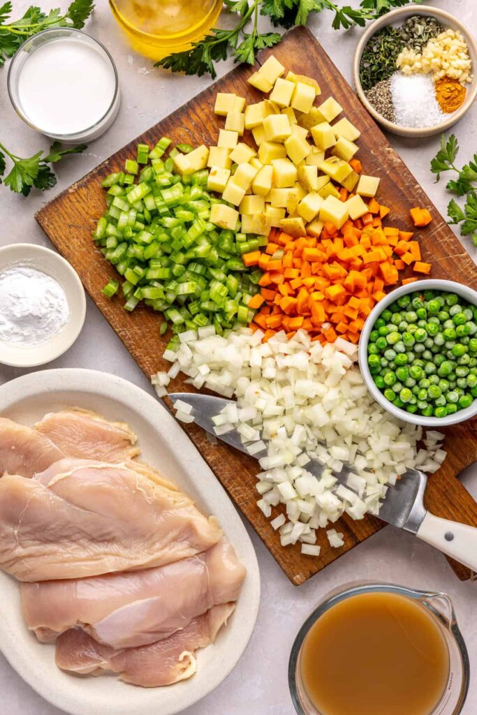Overhead shot of ingredients for homemade one pot chicken pot pie arranged on a cutting board and counter
