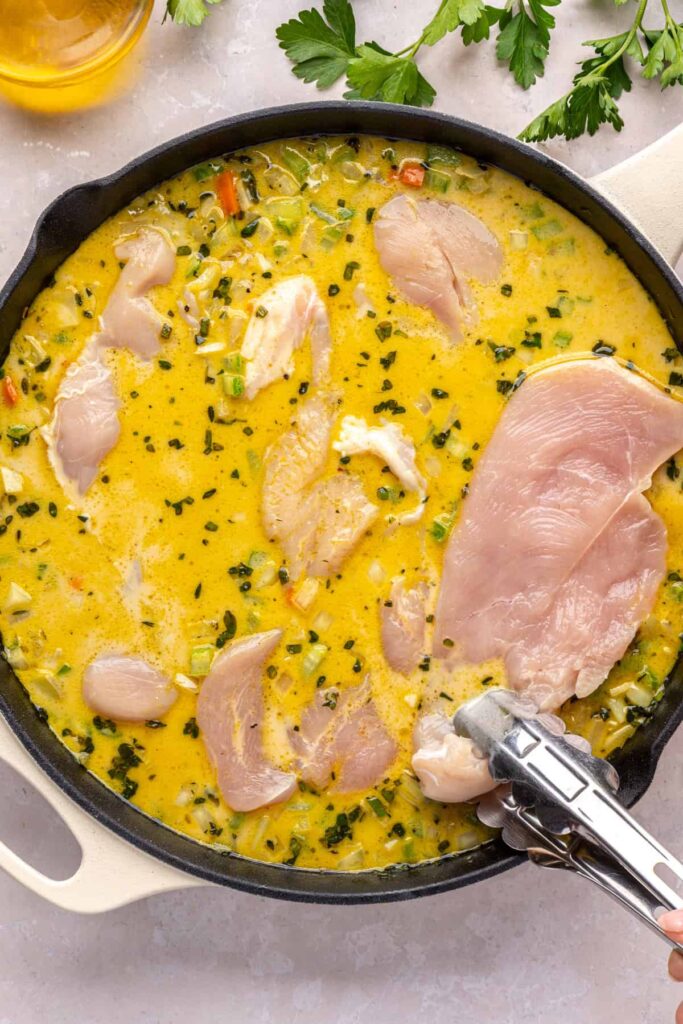 Chicken breasts placed into creamy vegetable mixture to cook in one pot chicken pot pie