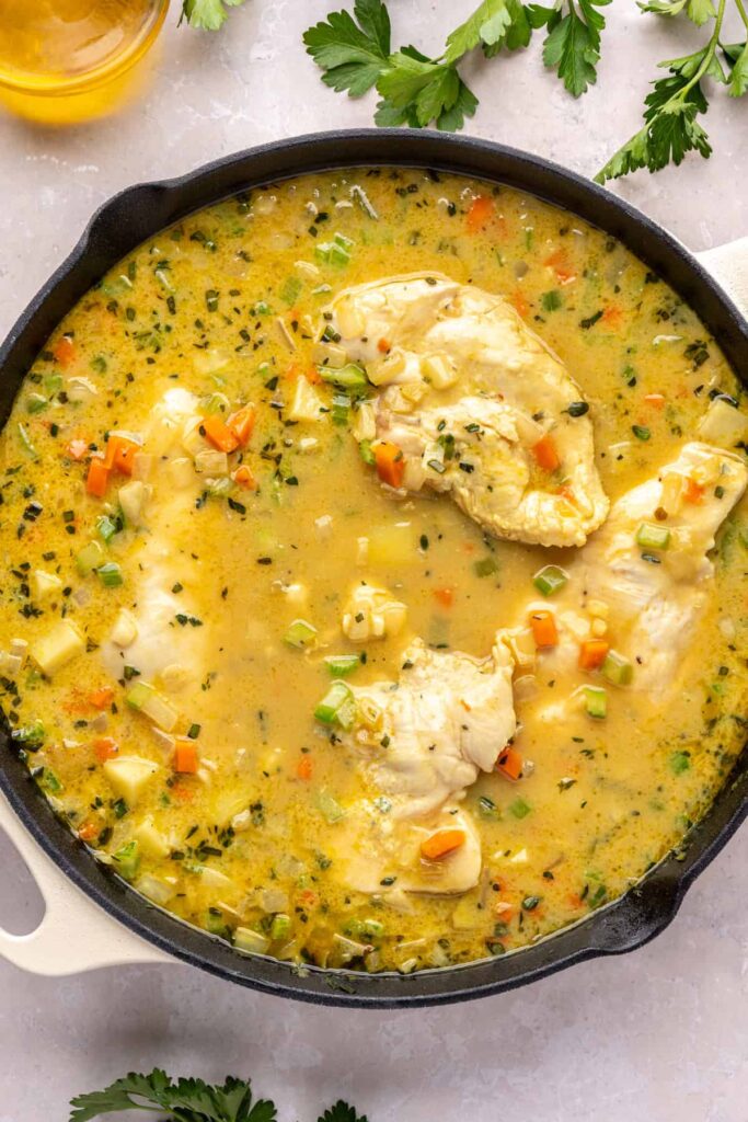 Chicken breasts placed into creamy vegetable mixture to cook in one pot chicken pot pie