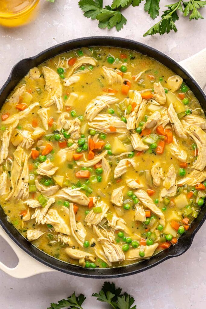 Chicken pot pie simmering in skillet as flavors meld before serving.