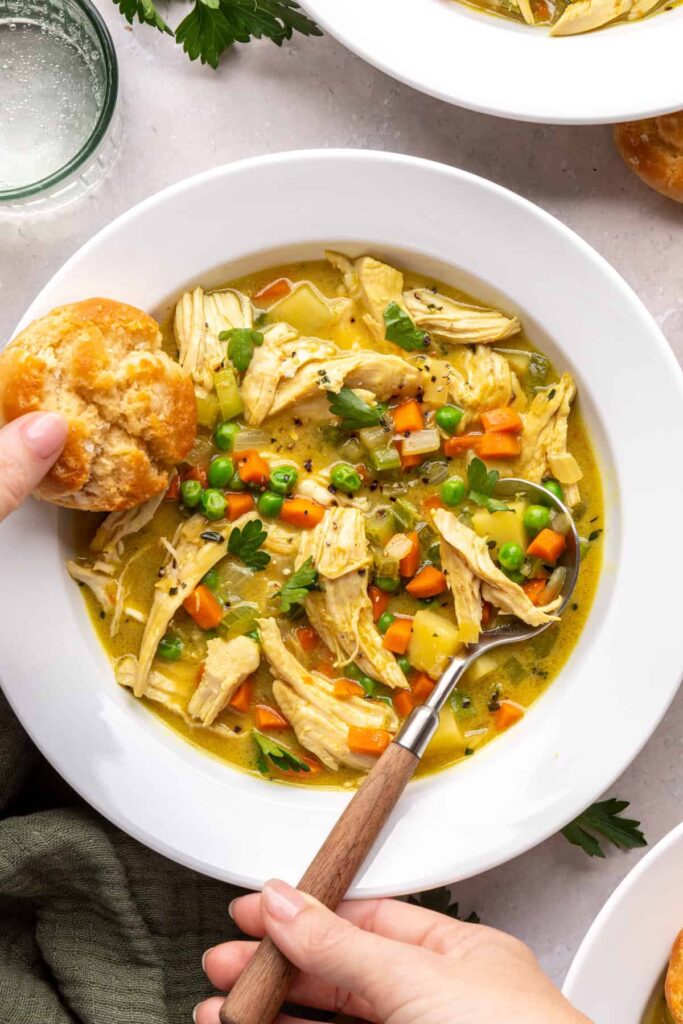close up, overhead shot of a Bowl of chicken pot pie with veggies and shredded chicken, biscuit on the side