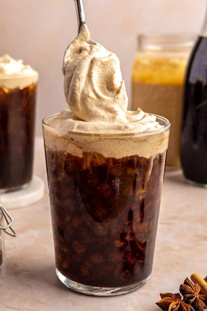 Pouring homemade pumpkin cold foam over iced coffee