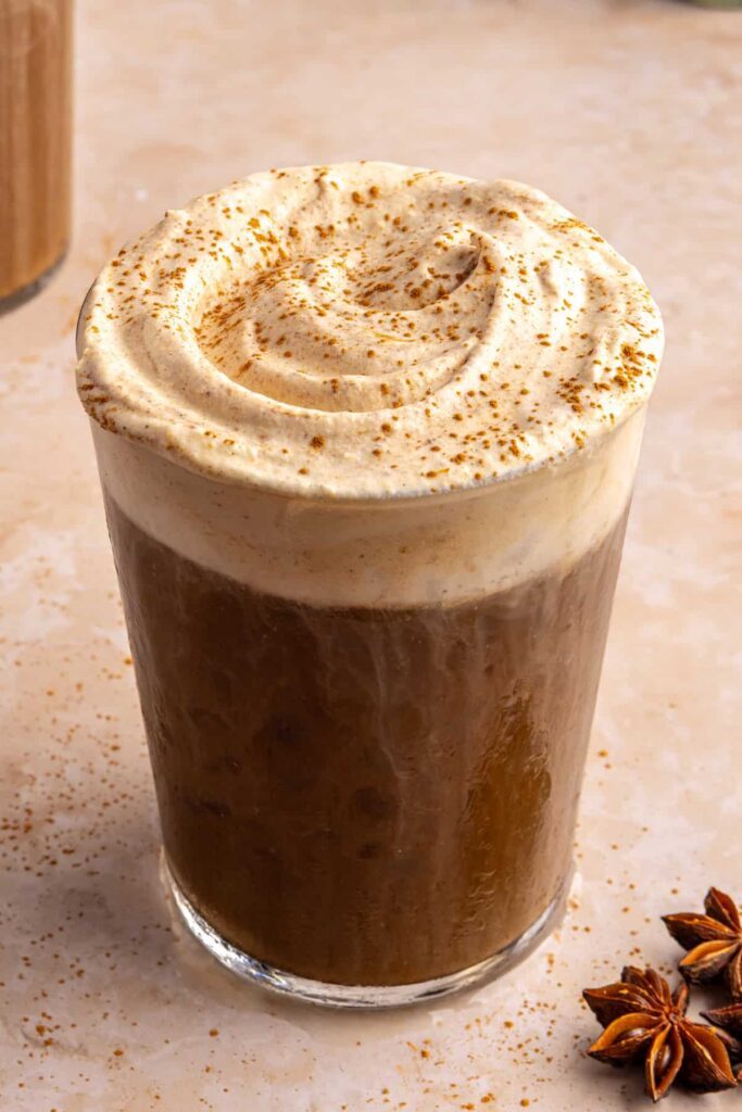 Pumpkin cold foam slightly mixed into iced coffee, still fluffy on top with a sprinkle of pumpkin pie spice