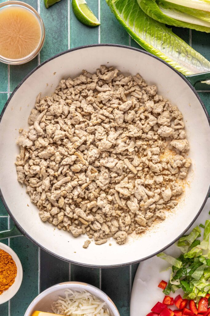 Ground turkey browning in a sauté pan with olive oil for easy turkey tacos