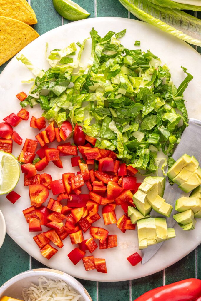 Fresh taco toppings including chopped romaine, red bell pepper, and avocado for turkey tacos