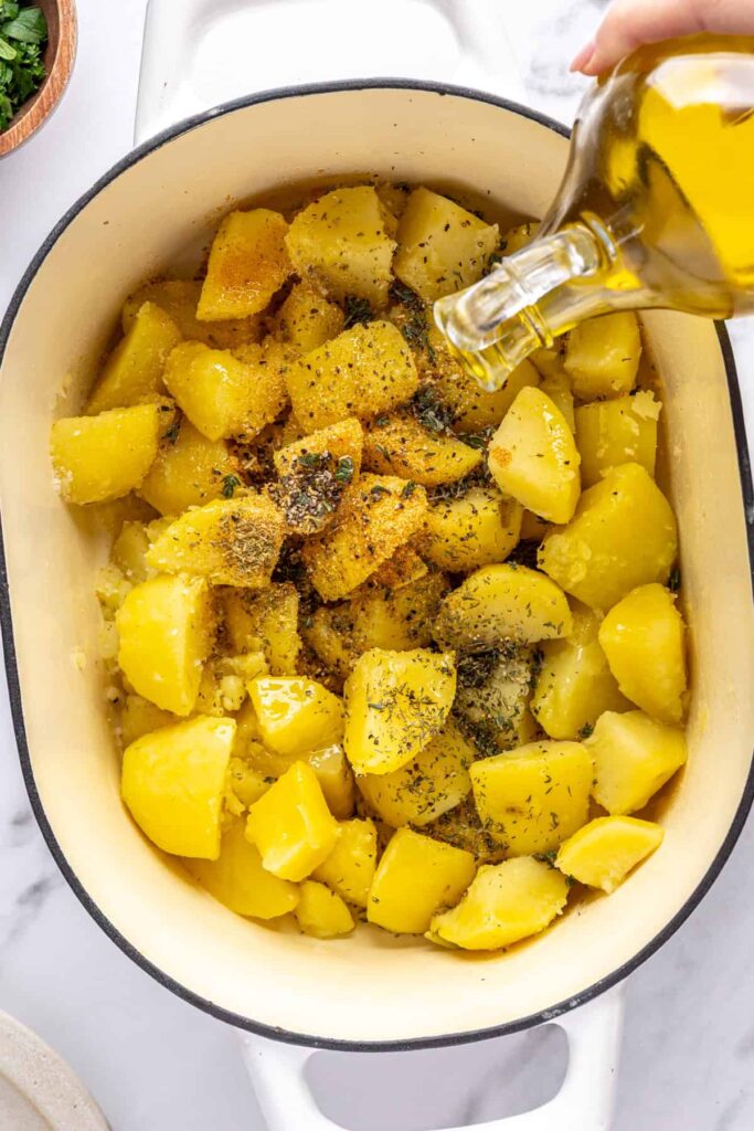 Olive oil and herbs poured over boiled potatoes for crispy English roast potatoes