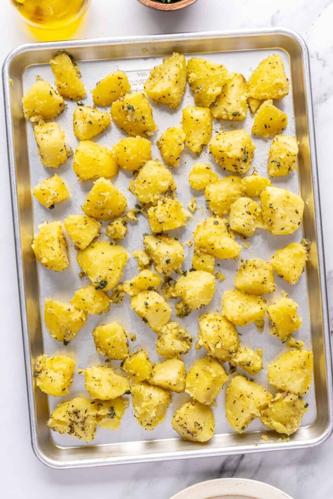 Potatoes arranged on an unlined baking sheet ready for roasting