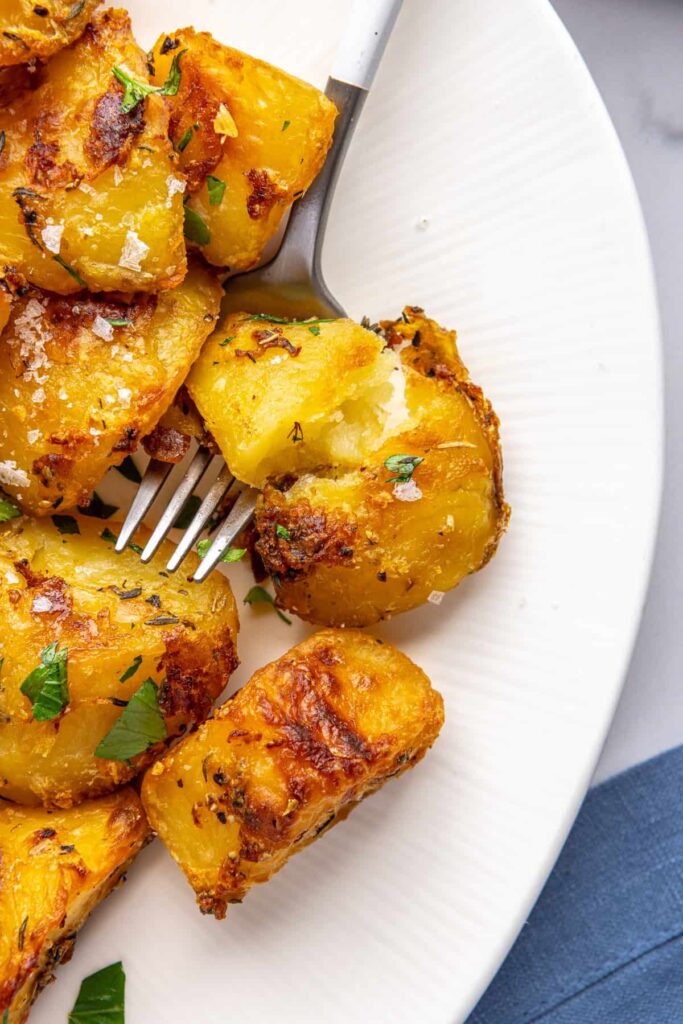 Crispy English roast potatoes served on a plate with a fork