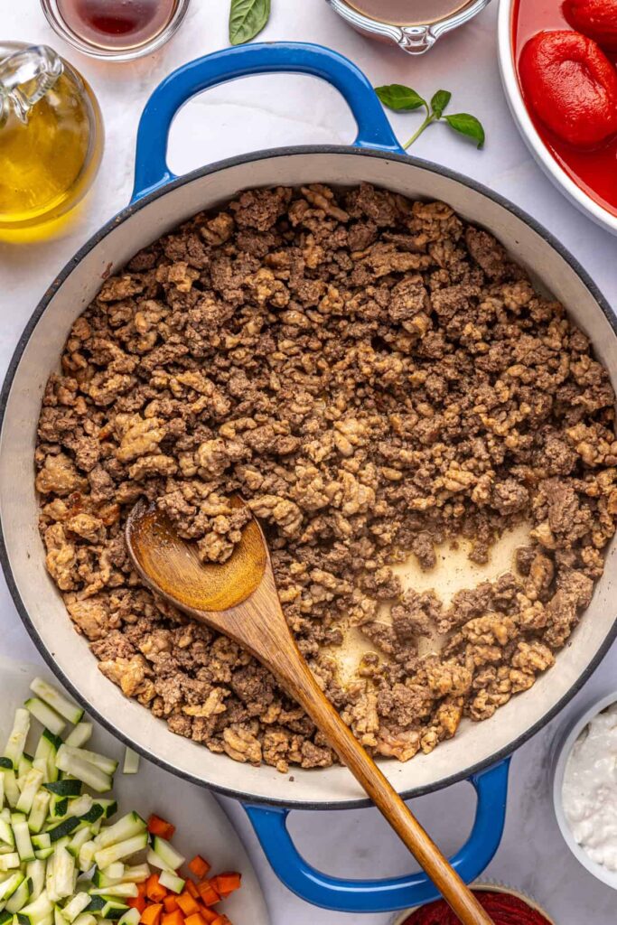 Ground meat cooking in a large pot for homemade vodka sauce, photographed from above