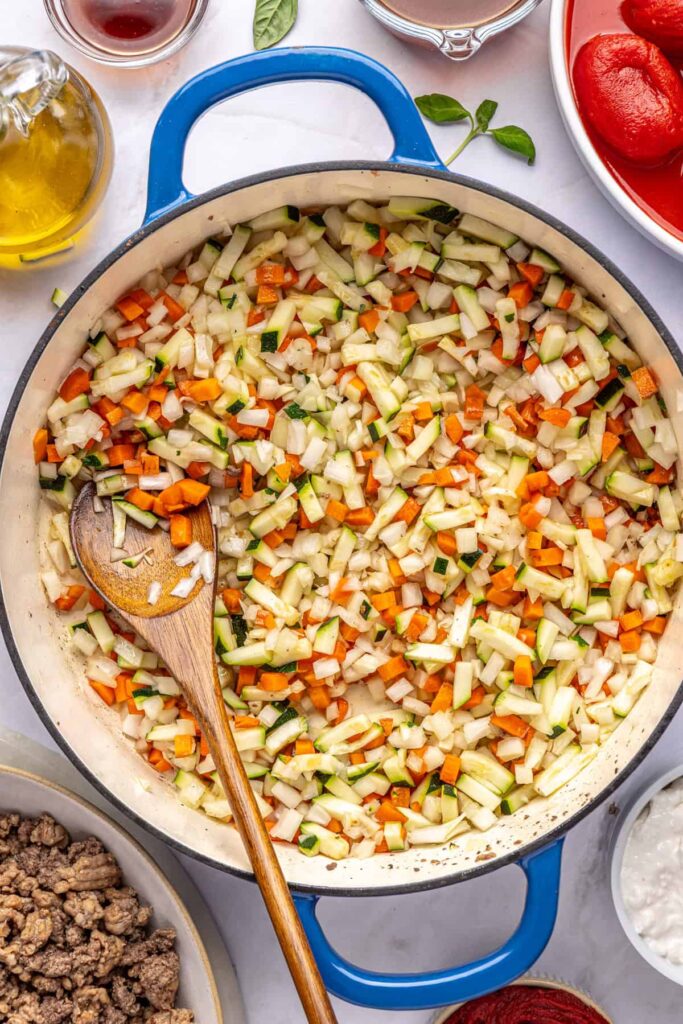 Overhead view of onion, zucchini, and carrot sautéing in a pot for hidden veggie vodka sauce