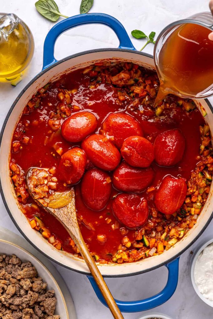 Tomatoes and broth added to the pot for homemade vodka sauce, overhead view