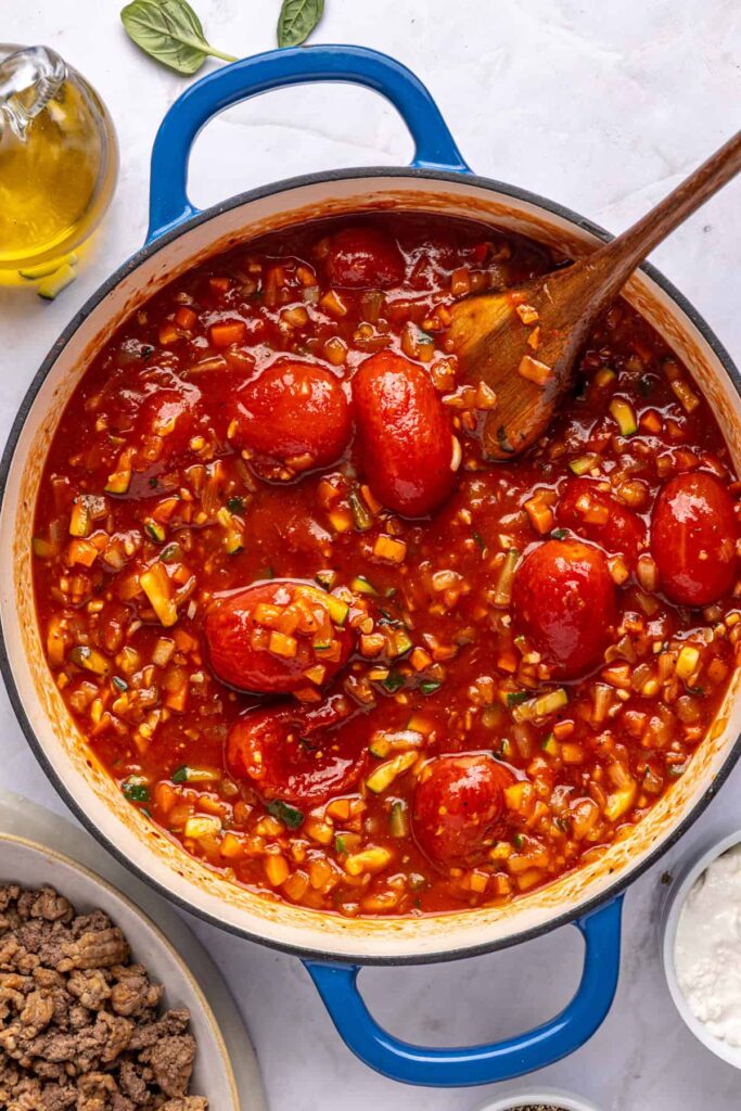 Vodka sauce simmering in a large pot with tomatoes and broth, photographed overhead