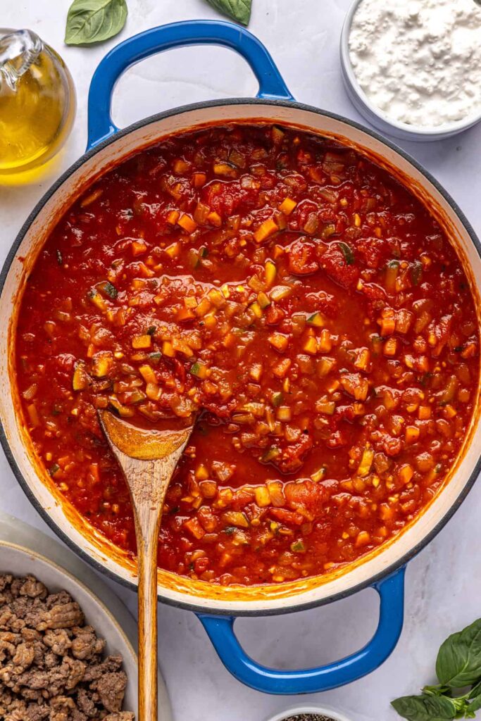 Vodka sauce simmering in a large pot with tomatoes and broth, photographed overhead