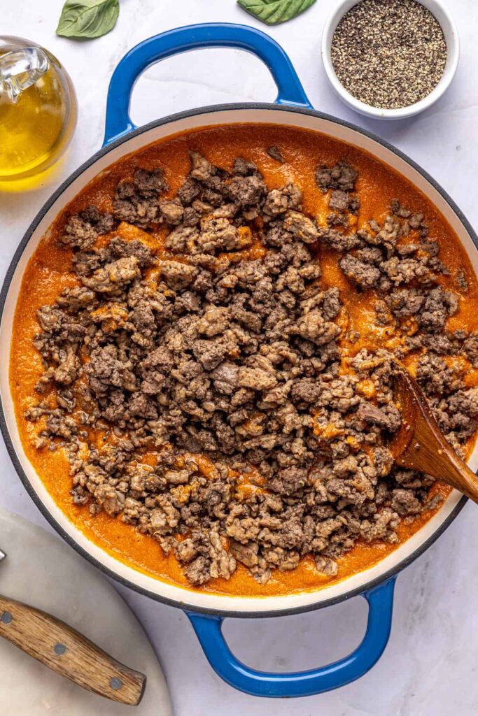 Overhead view of meat being added back into blended vodka sauce