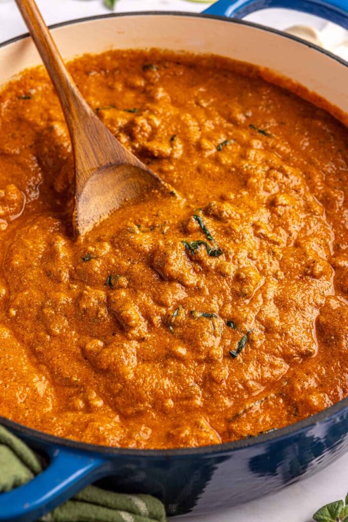 Close-up overhead shot of creamy homemade vodka sauce in a Dutch oven with a wooden spoon