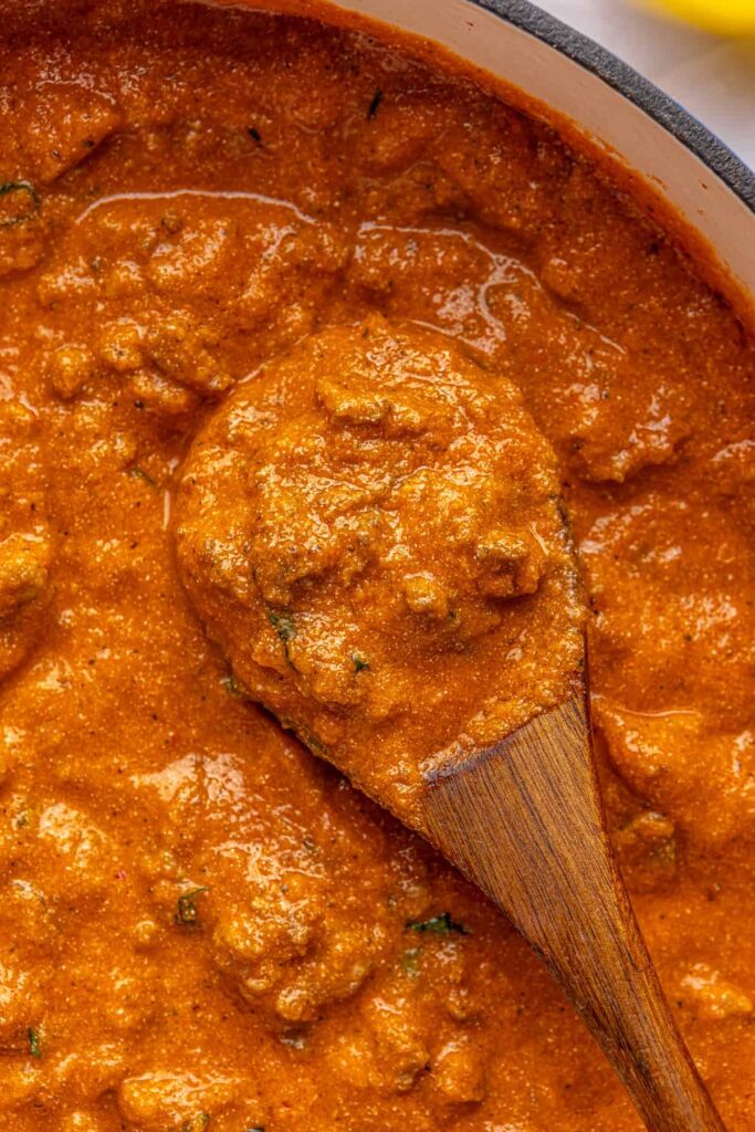Thick, creamy vodka sauce with hidden veggies, photographed overhead in a Dutch oven with a wooden spoon