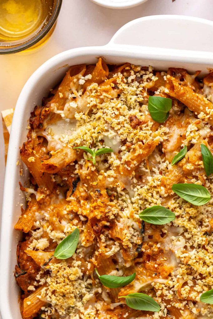 Golden, bubbly baked ziti fresh out of the oven and garnished with fresh basil, overhead shot