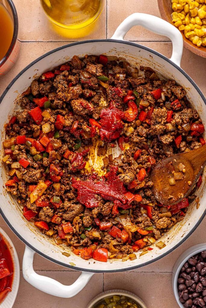 Tomato paste melting into spiced beef mixture for chipotle beef & black bean soup