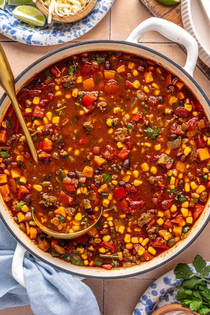 Overhead shot of finished chipotle beef & black bean soup in the cooking pot, with a ladle