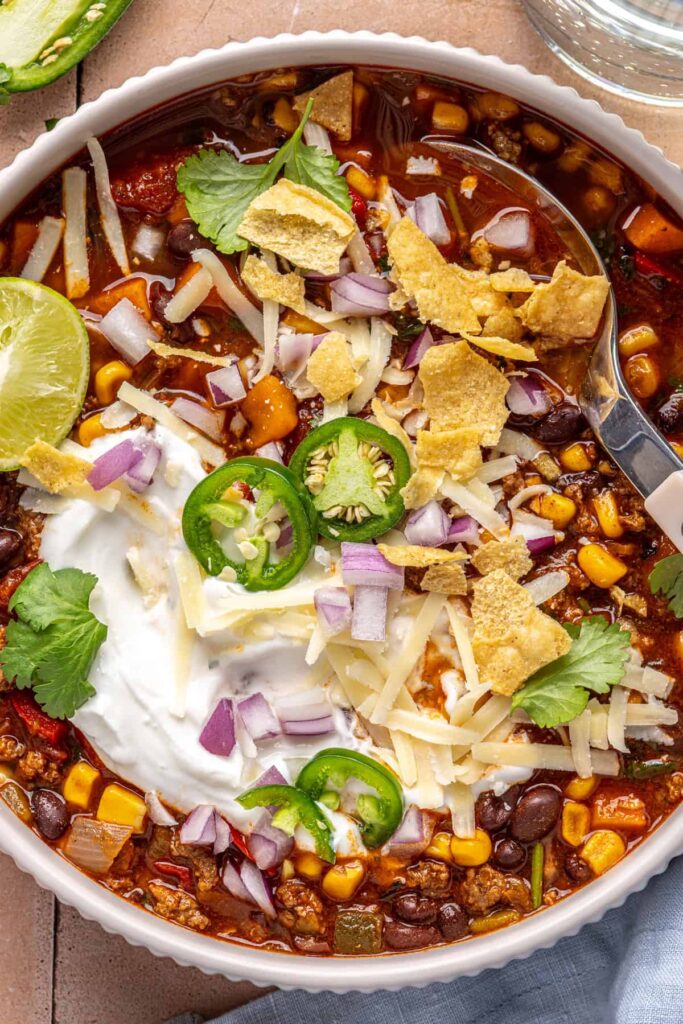 close-up photo of Chipotle beef & black bean soup garnished with cilantro, jalapeños, and crushed tortilla chips