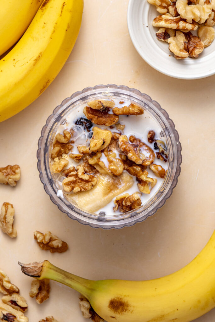 All banana nut smoothie ingredients layered in high-speed blender before blending