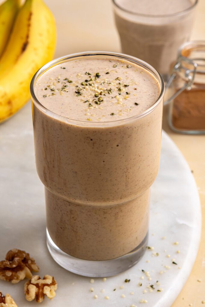 Creamy banana nut smoothie in glass topped with hemp seeds