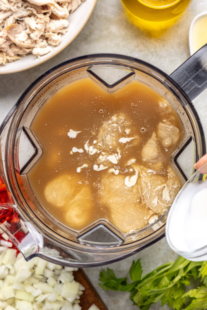 Preparing creamy base for cajun chicken soup in a blender with cannellini beans, broth, and coconut milk