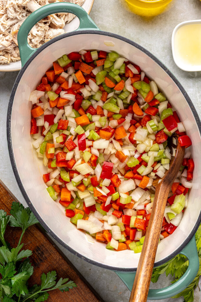 Diced onion, carrot, celery, and red bell pepper sautéing in pot for cajun chicken soup