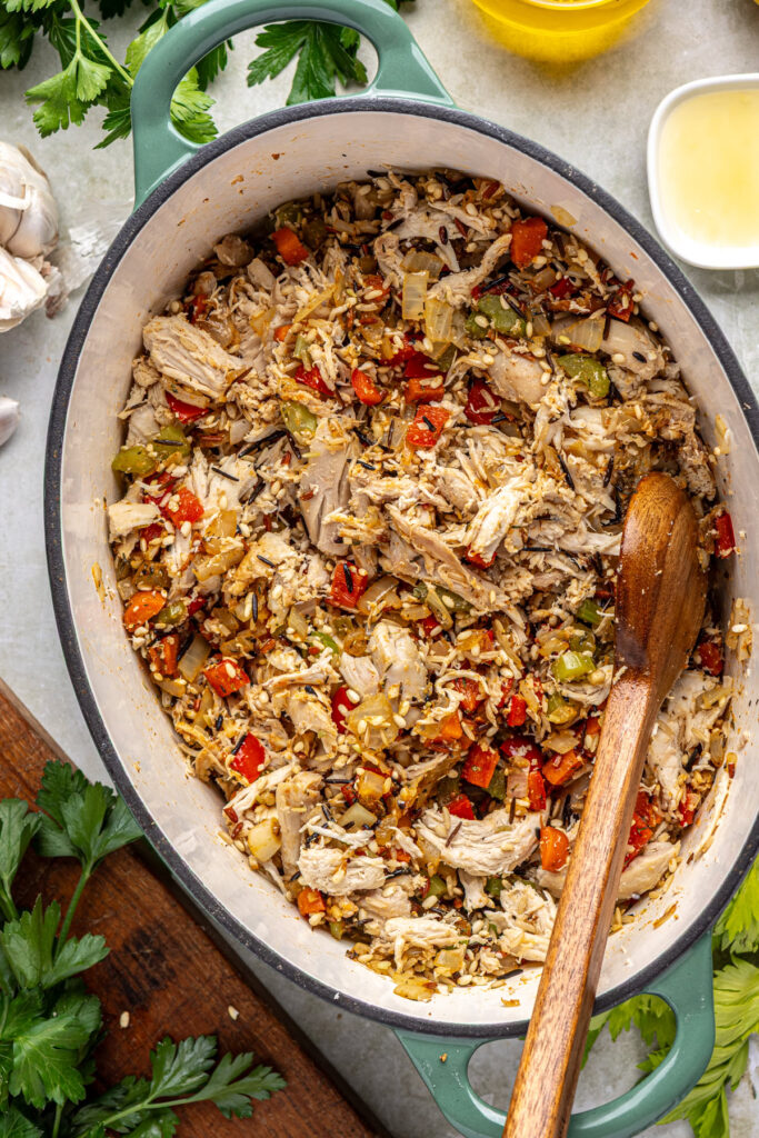 Mixing chicken and wild rice into seasoned vegetables for soup