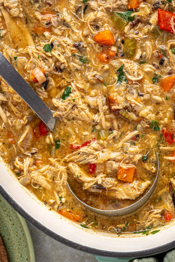 close-up of ladle scooping creamy cajun chicken soup from pot
