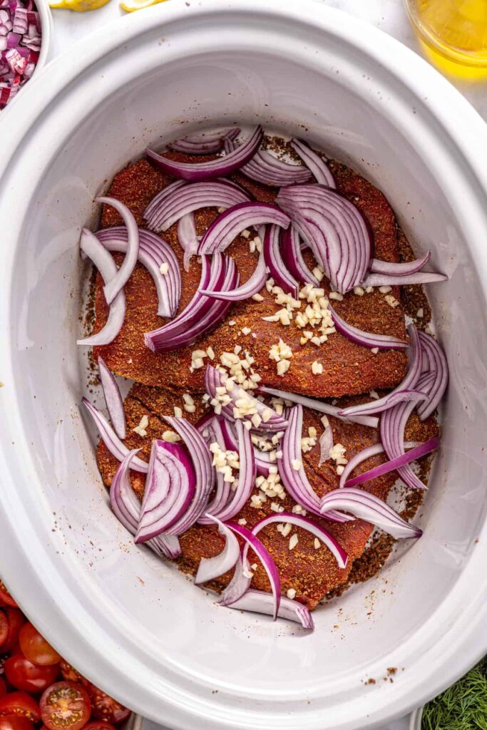 Flank steak with red onion and garlic in a slow cooker for Greek beef bowls