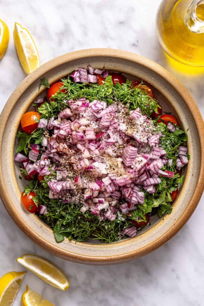 Fresh tomato relish with herbs and lemon in a bowl, ready to be mixed