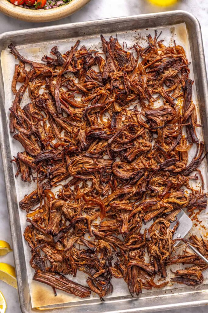 Shredded Greek beef broiled until crispy on a parchment-lined sheet pan