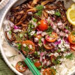 close-up, overhead view of crispy Greek beef bowls with rice, tomato relish, feta, and lemon wedge