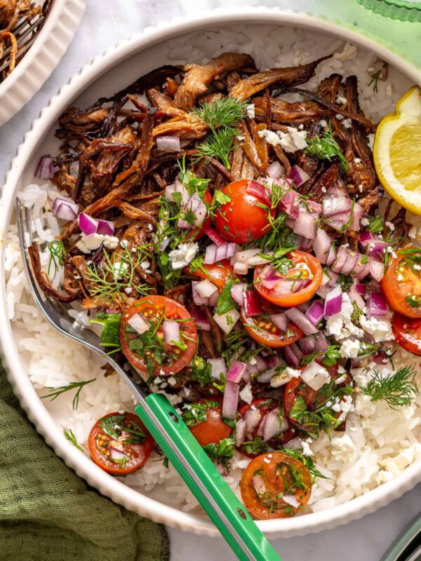 close-up, overhead view of crispy Greek beef bowls with rice, tomato relish, feta, and lemon wedge
