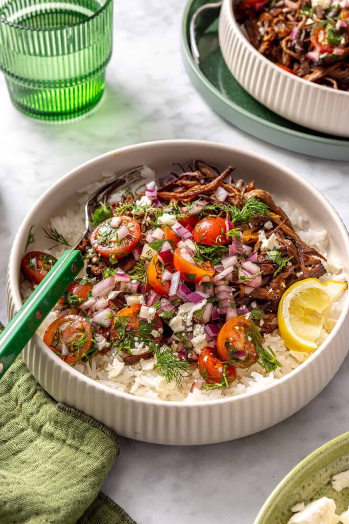 Crispy Greek beef bowls with rice, tomato relish, feta, and lemon wedge