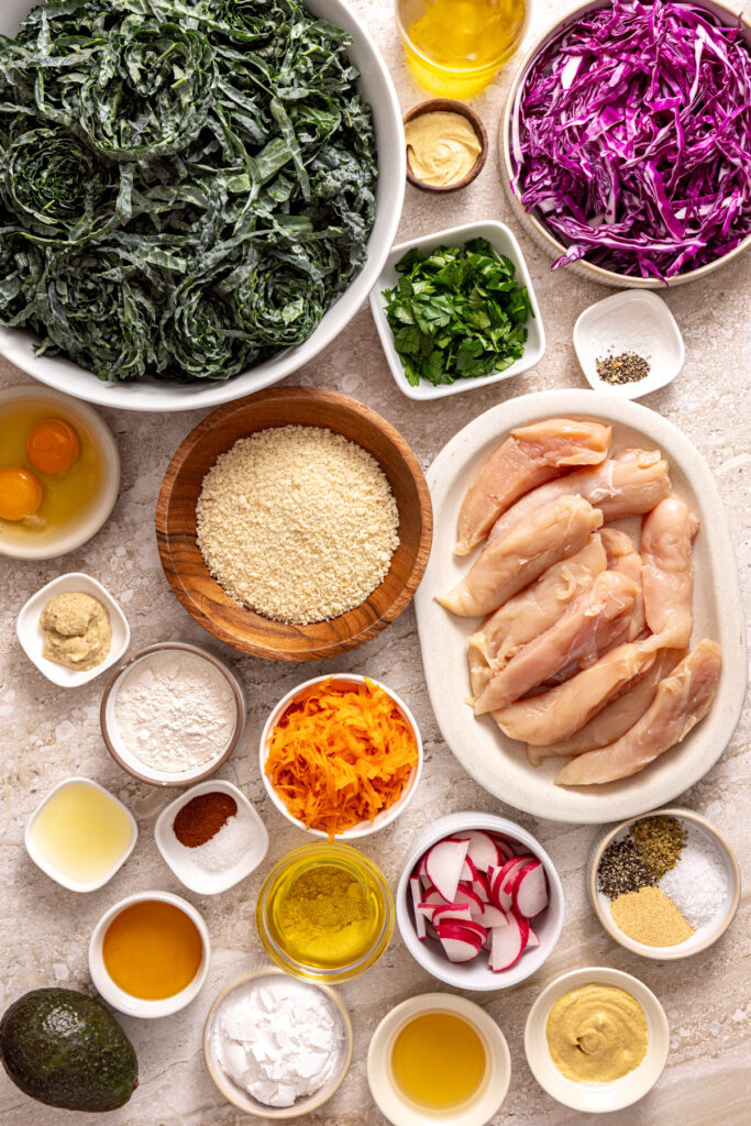 Overhead view of kale, chicken tenders, cabbage, carrots, radishes, and honey mustard ingredients