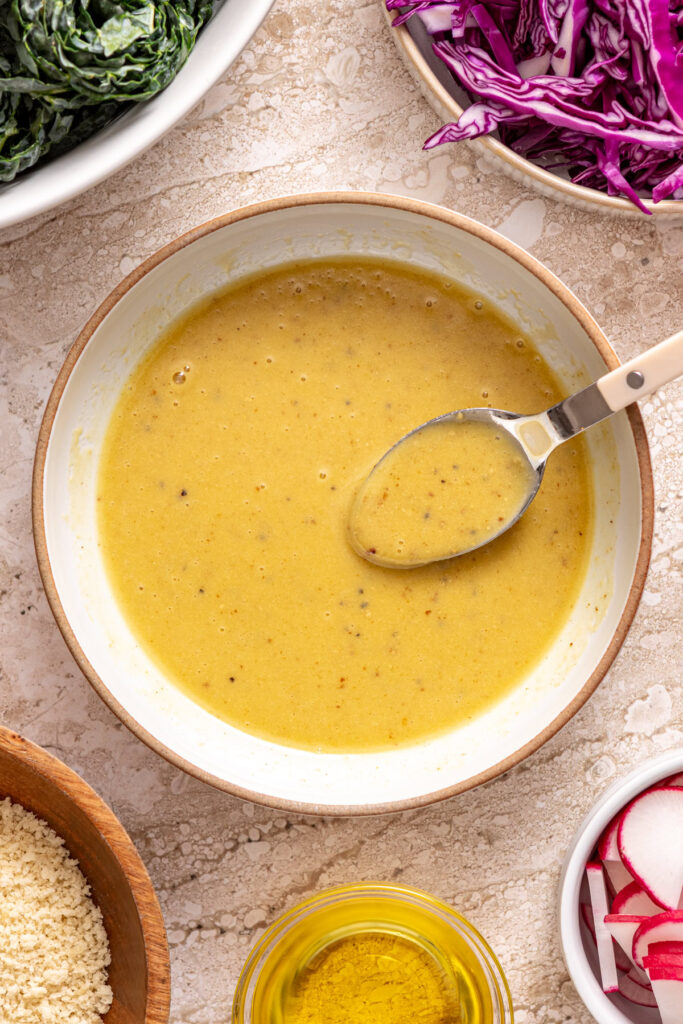 Emulsified honey mustard dressing in white bowl with a spoon