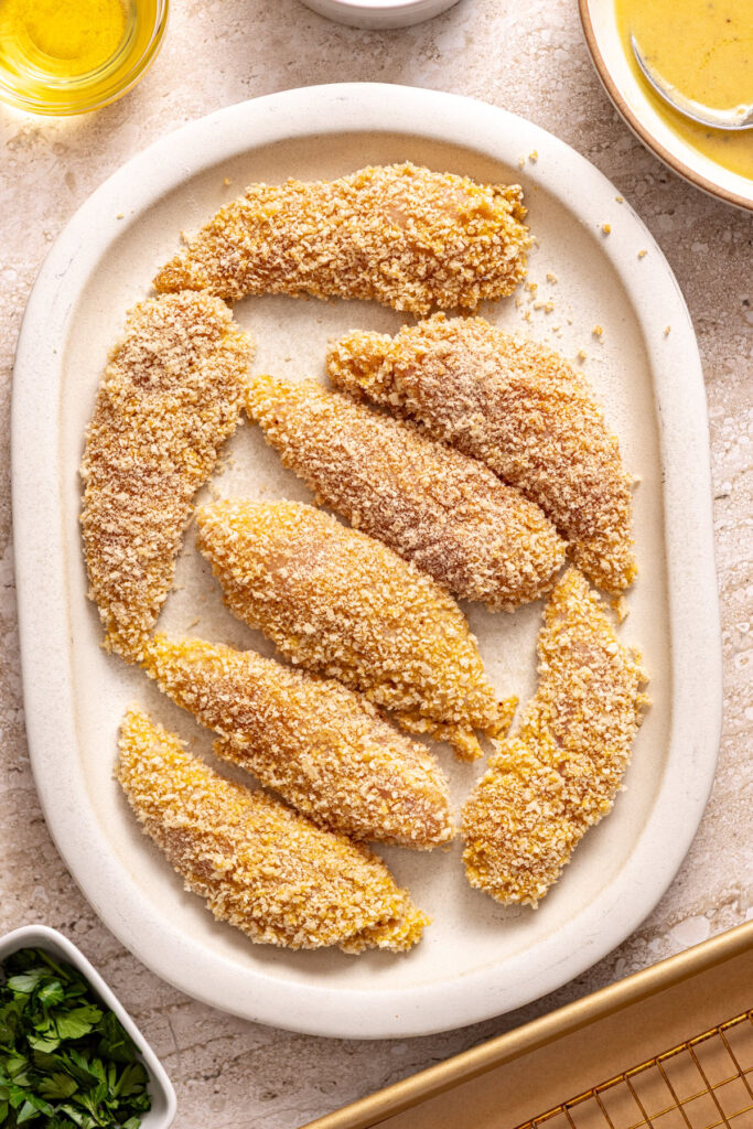 chicken tenders coated in gluten-free panko breadcrumbs before pan frying and baking